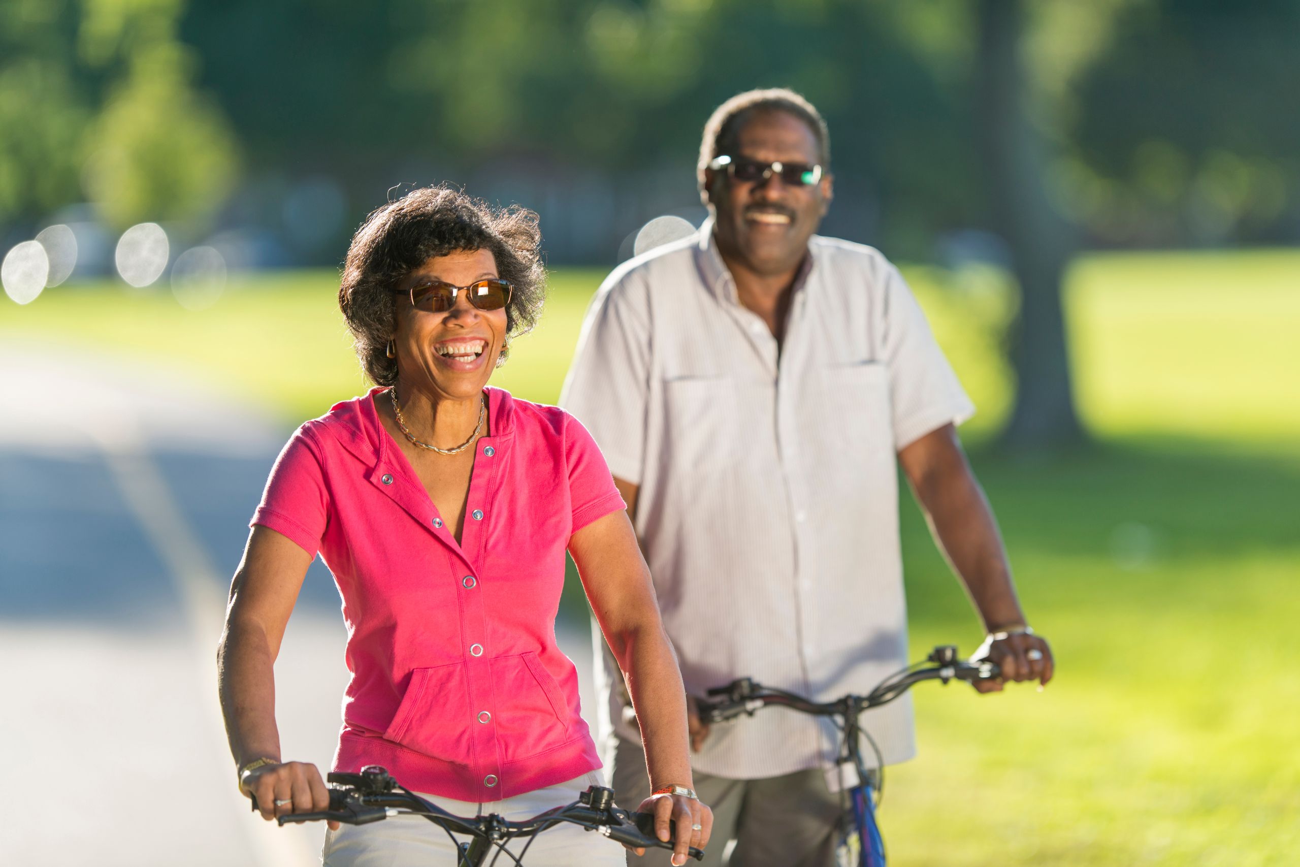 A happy man and woman riding bikes together outside