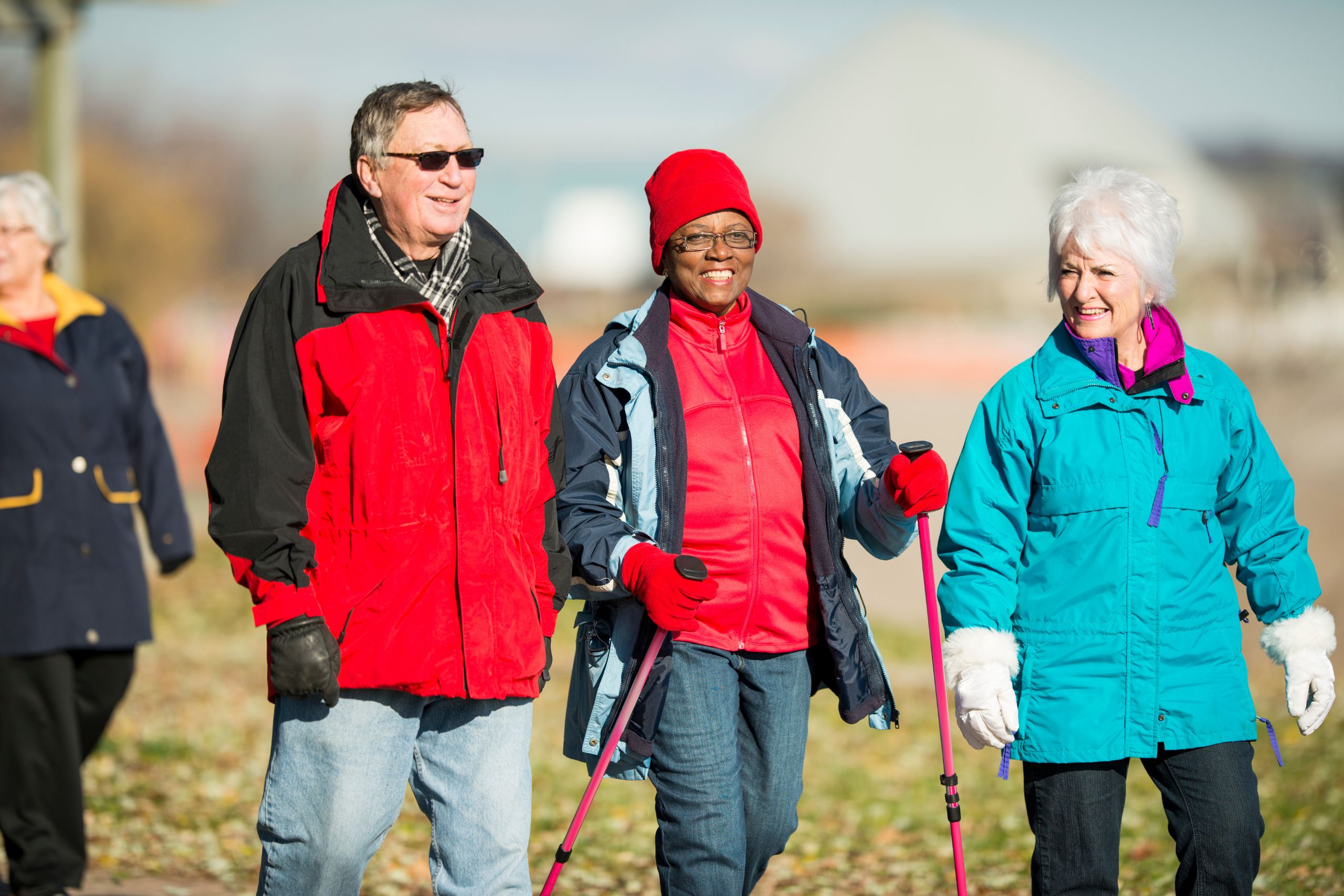 A group of happy, bundled-up elderly hikers walking together outside.