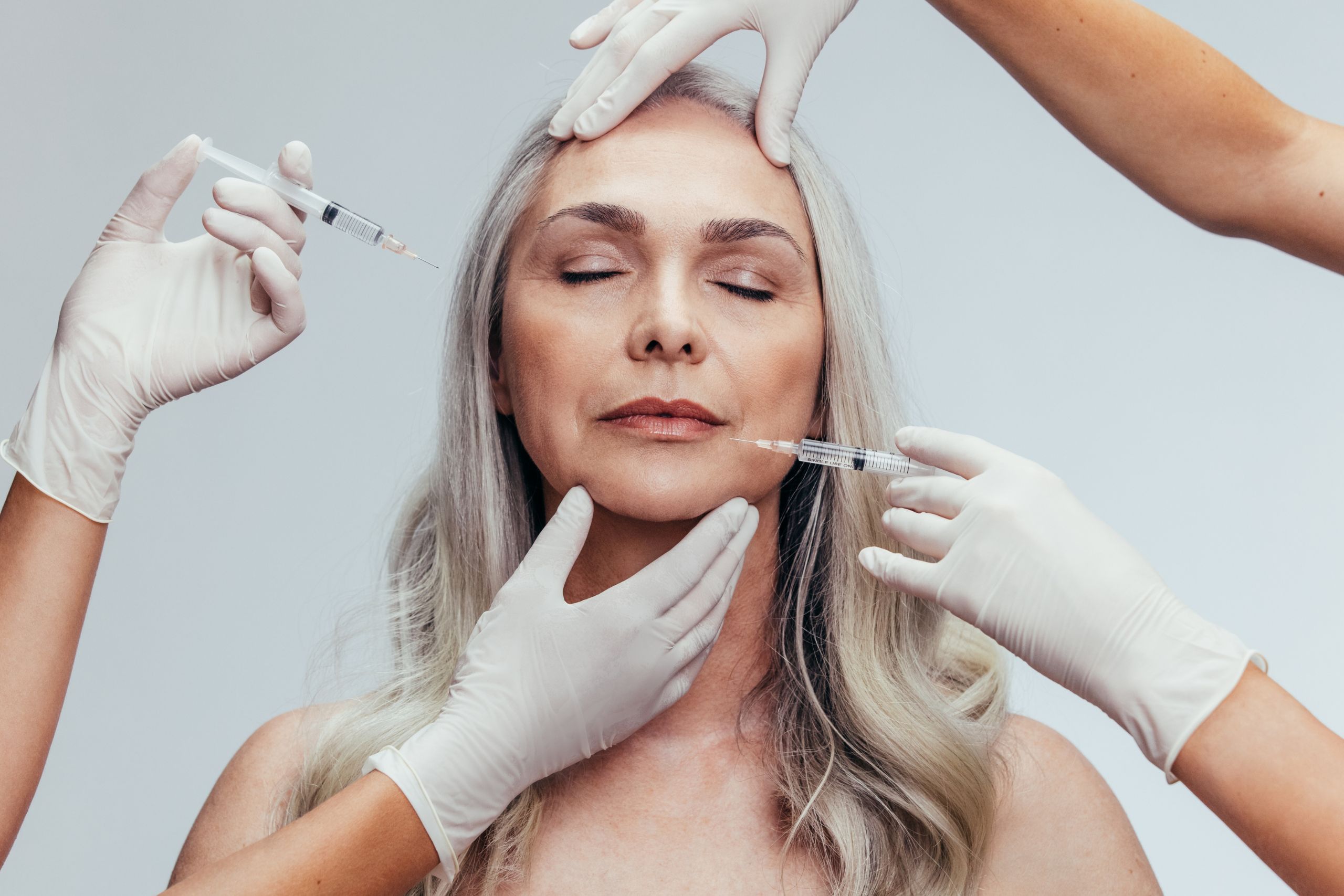 An artistic close-up of a middle-aged woman receiving facial injections